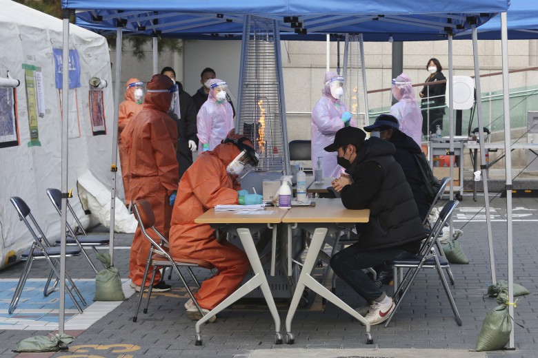Медицинские работники тестируют предполагаемых заболевших коронавирусом в передвижном центре в Сеуле. Фото Ahn Young-joon